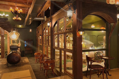 A cozy vintage Cleocatra cafe with wooden furniture, arched windows, antique lamps, and warm lighting