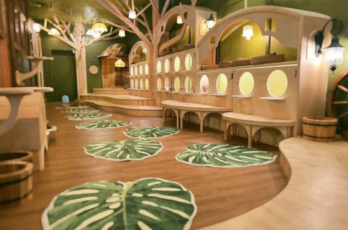 A whimsical play area for the cats at Cleocatra cafe with tree-shaped structures, circular cubbies, and leaf-patterned rugs on wooden floors